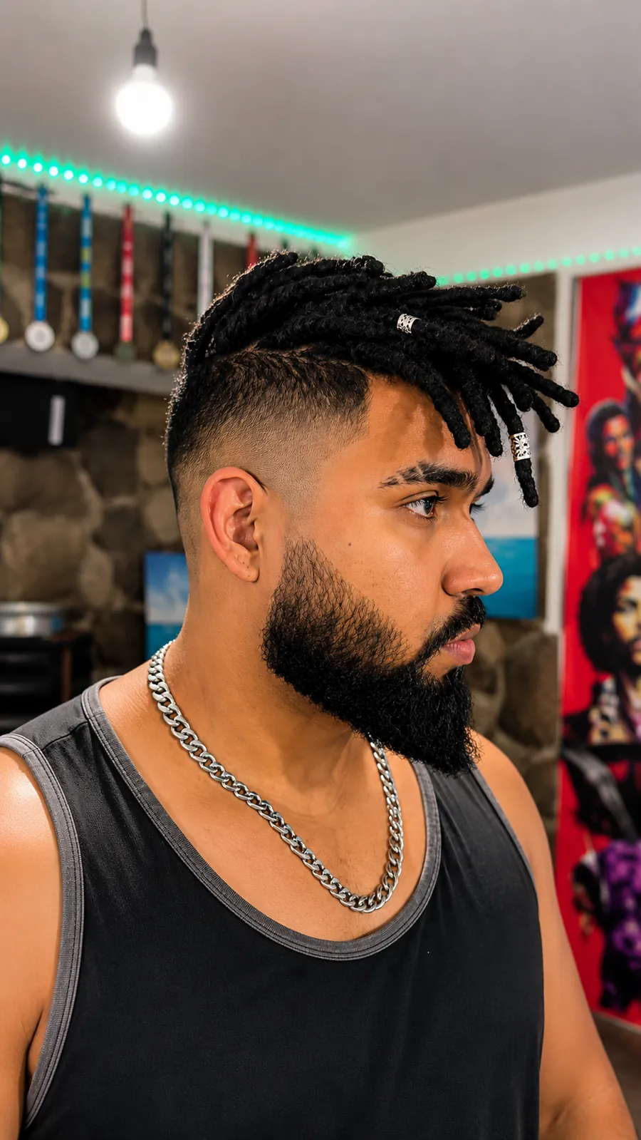 Hombre con moicano de dreads negros y anillos plateados, de perfil
